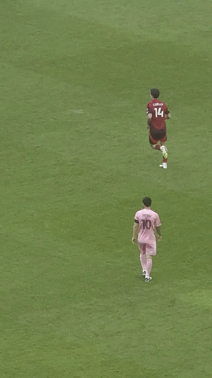 Two players on a green pitch seen from above, one in maroon and one in pink.