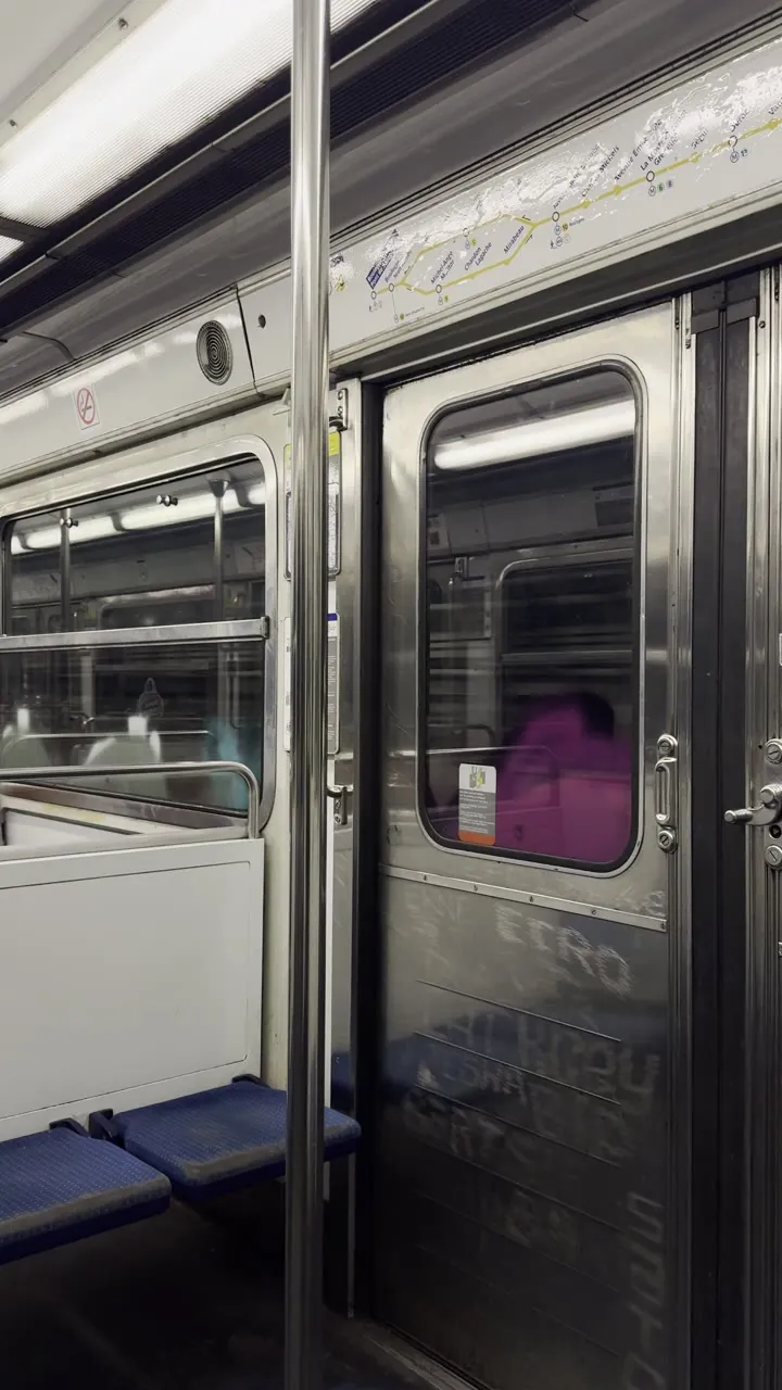 Train carriage interior with metal sliding doors and blue seats.