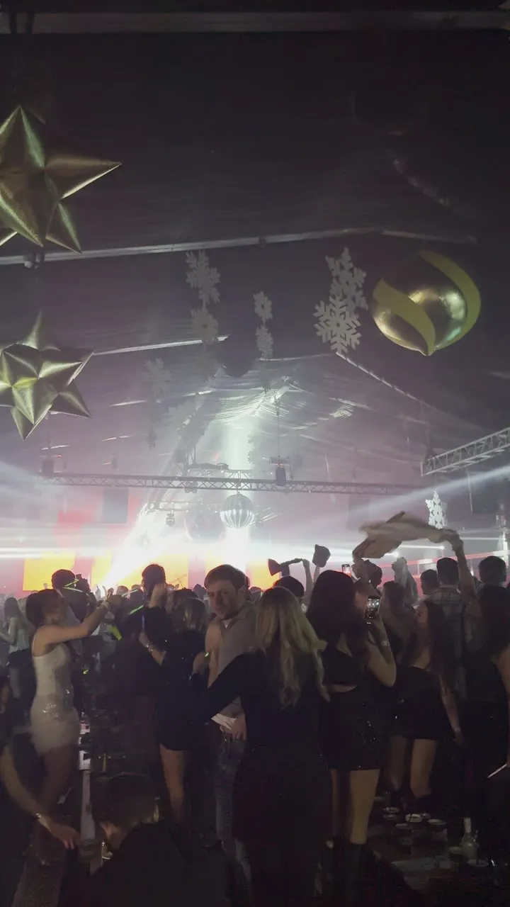 Crowd of people dressed up at a party under a ceiling with gold star decorations.
