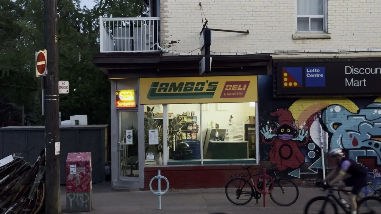 Street corner shopfront beside a graffiti mural, with parked bikes.