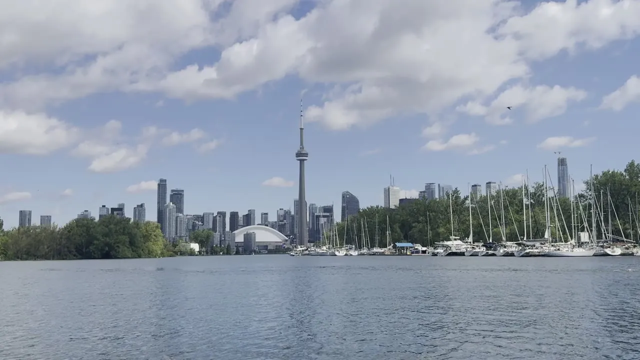City skyline with a tall tower across a lake, under a cloudy sky.