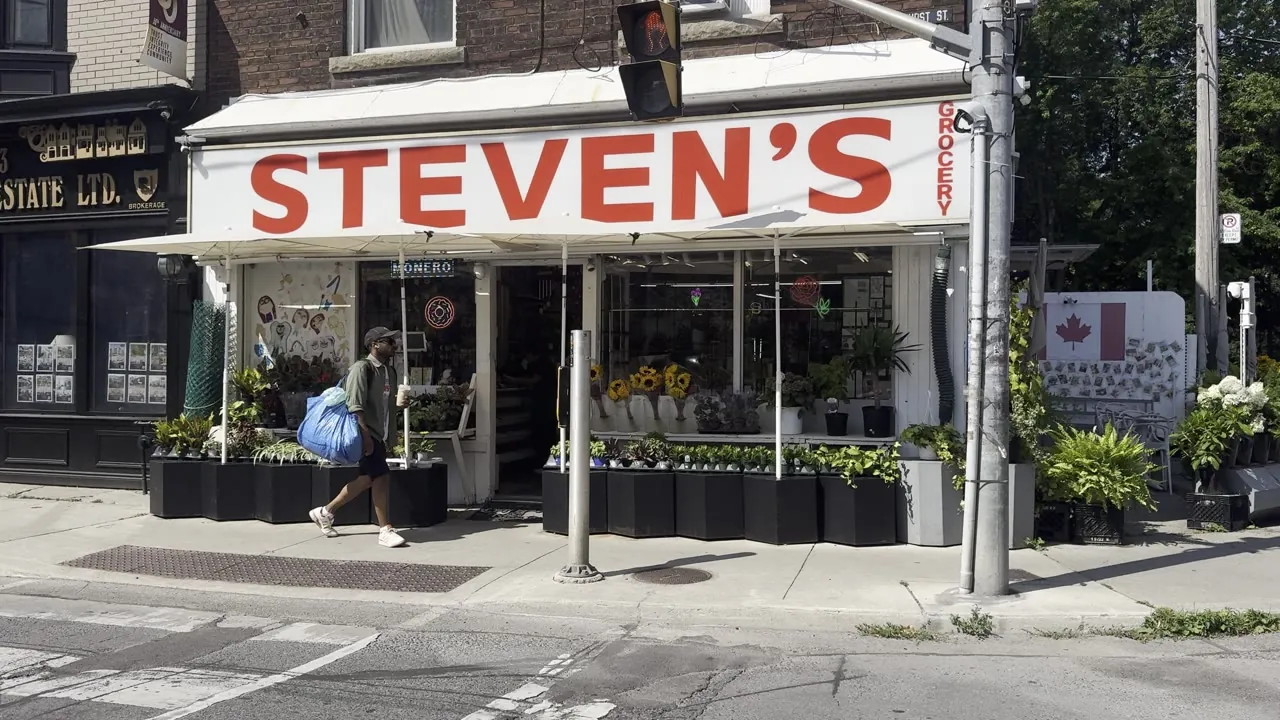 Corner shop with a red awning and a large Steven’s sign.