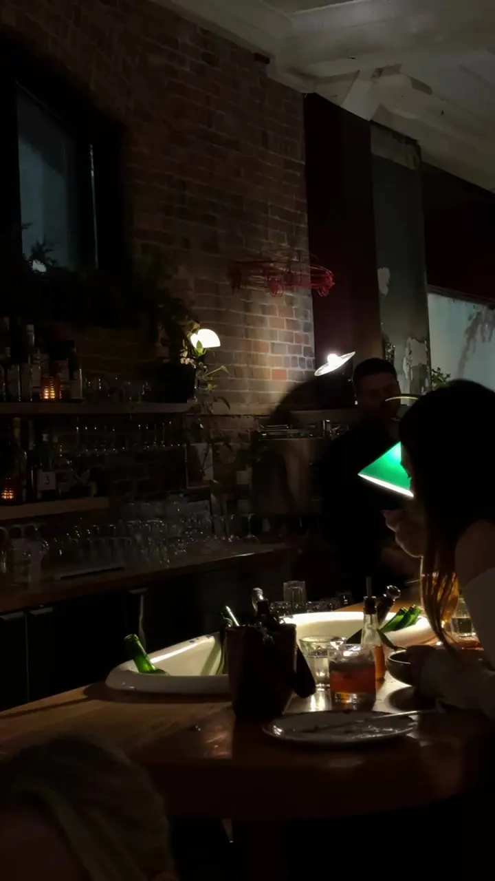 Dim bar with a green lamp and people at the counter.